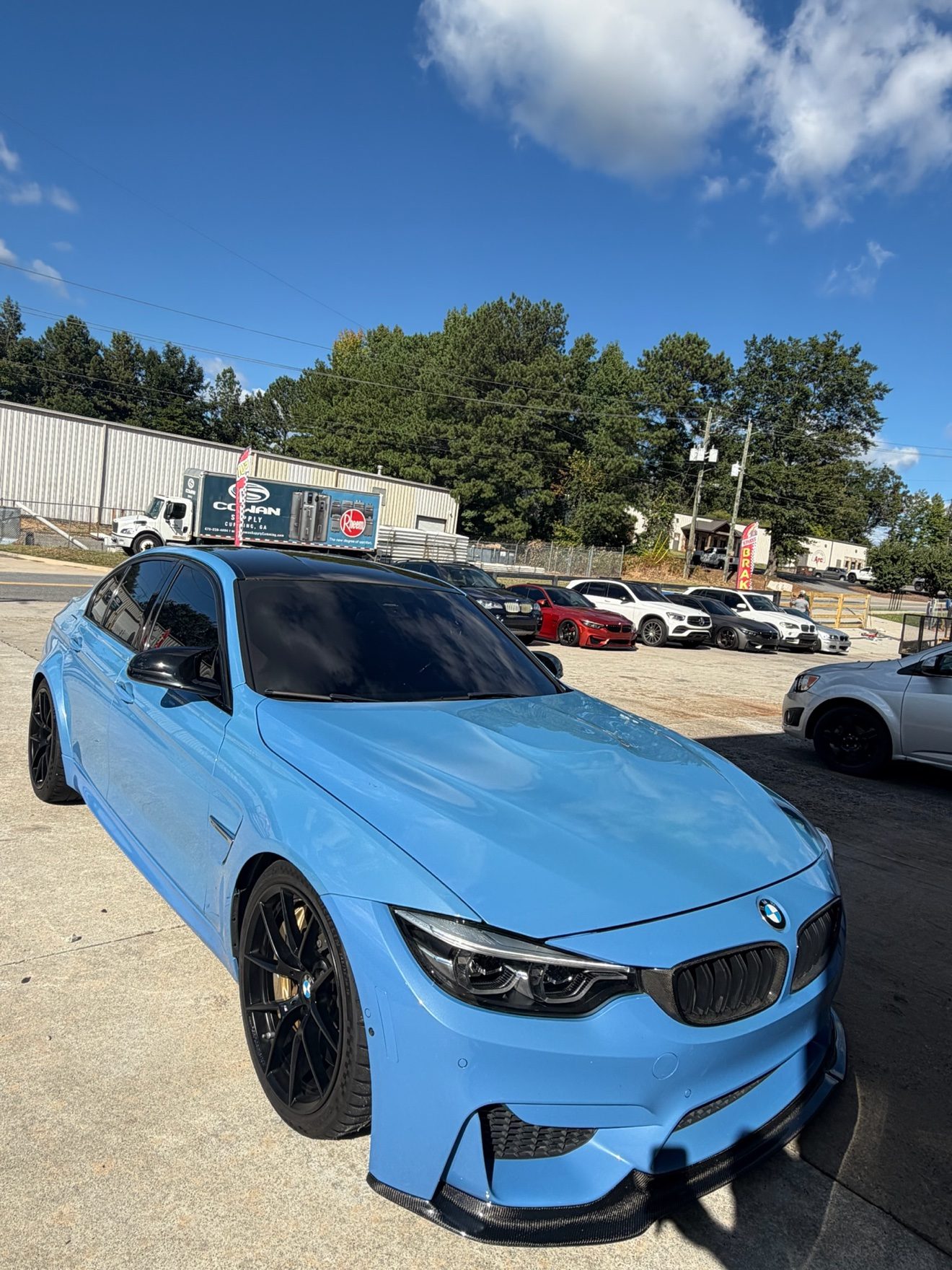 Blue BMW M3 sedan at the Auto Haus Solutions shop lot