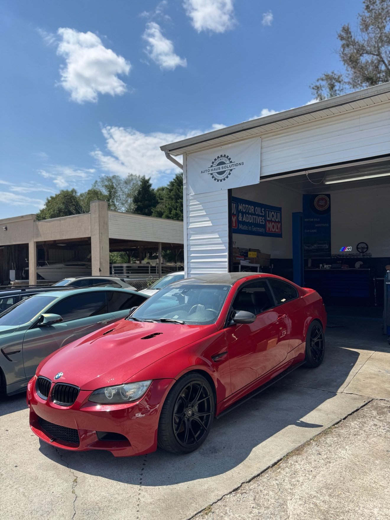 Red BMW M3 coupe at the Auto Haus Solutions service bay entrance