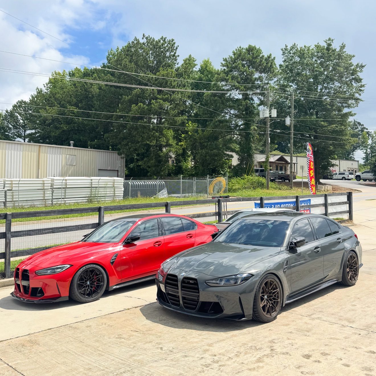 Red and gray BMW M3 sedans at the Auto Haus Solutions shop