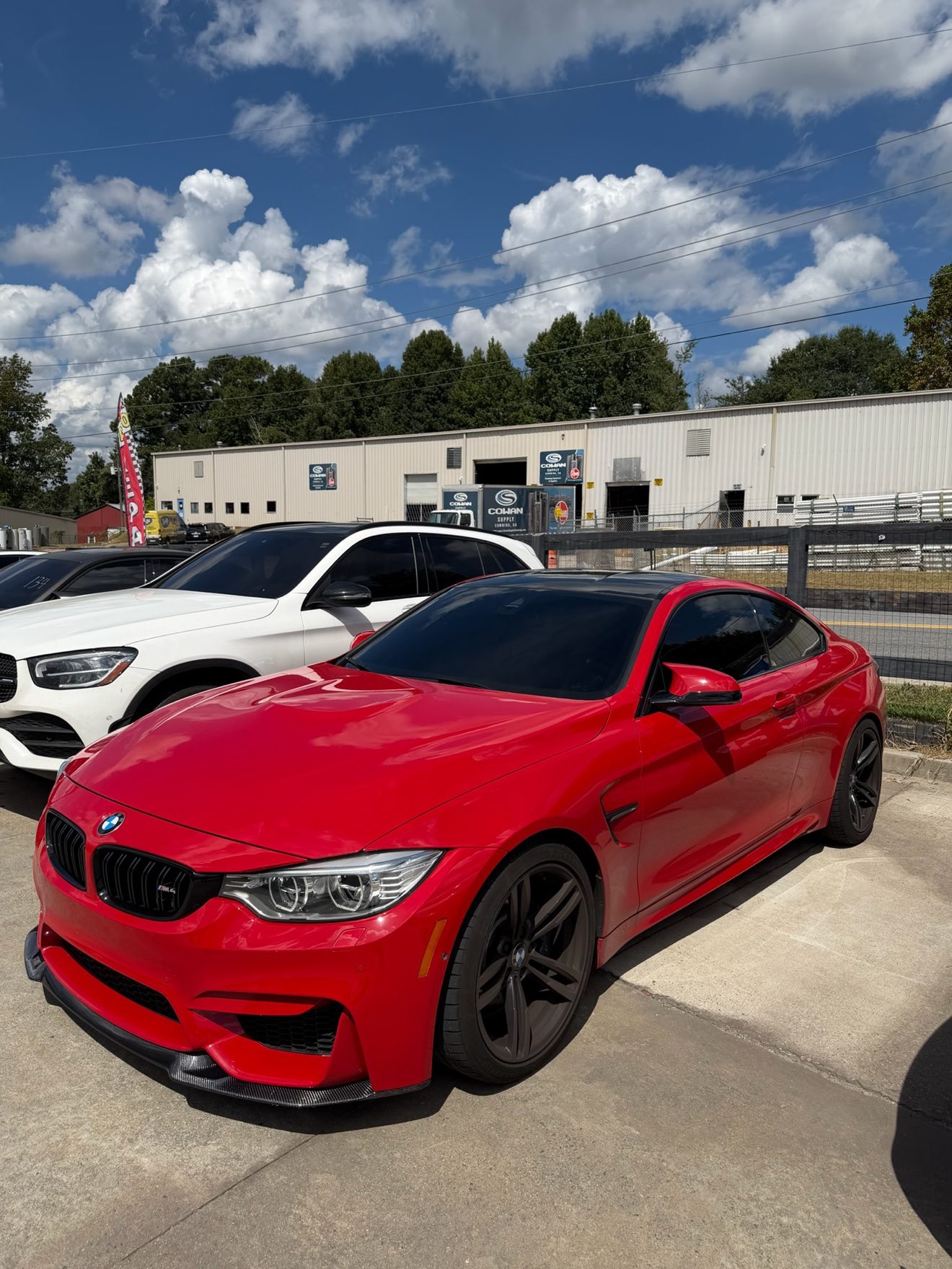 Red BMW M4 coupe and white Mercedes-Benz GLC at Auto Haus Solutions
