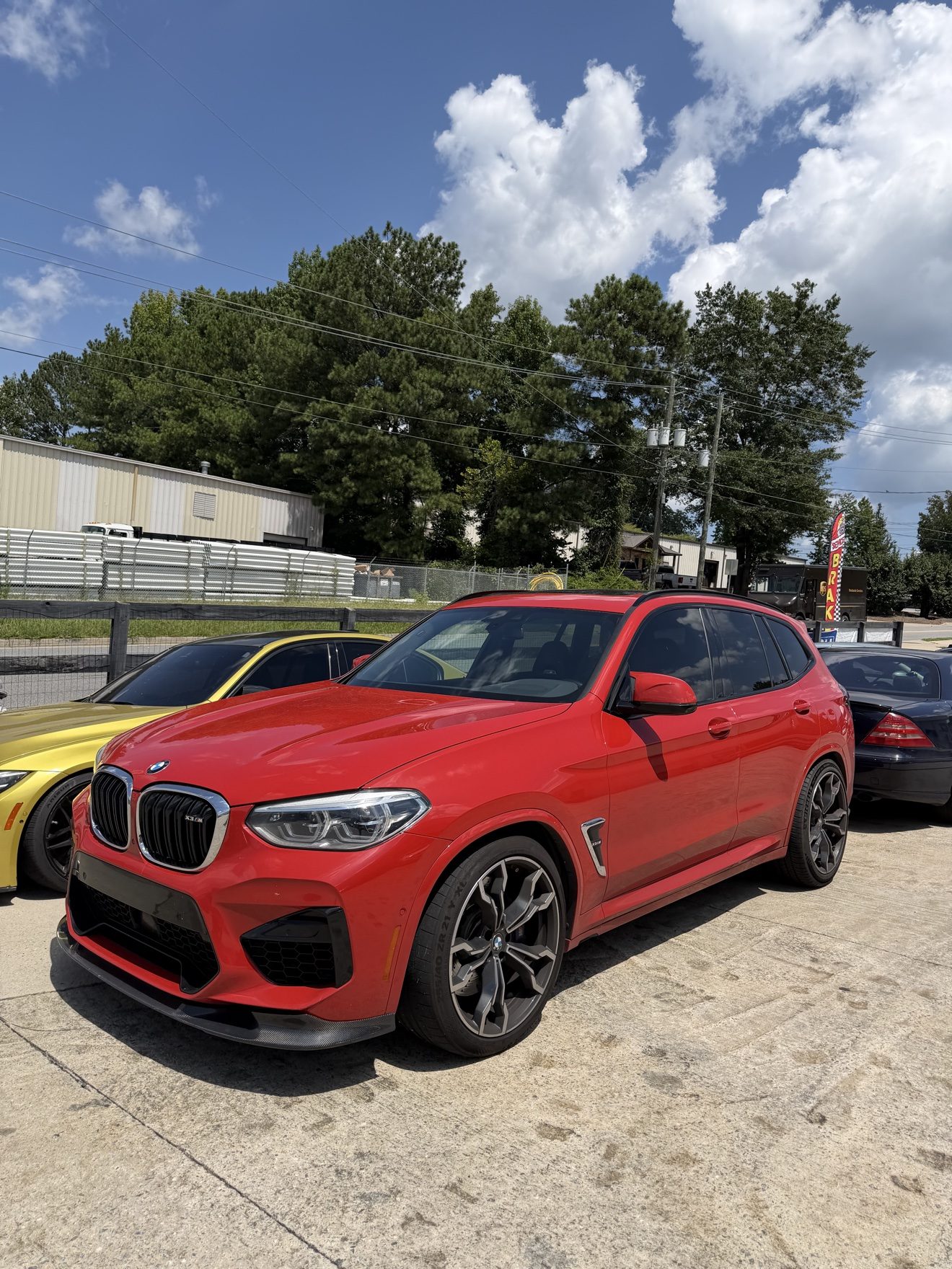 Red BMW X3M and yellow BMW M4 at Auto Haus Solutions