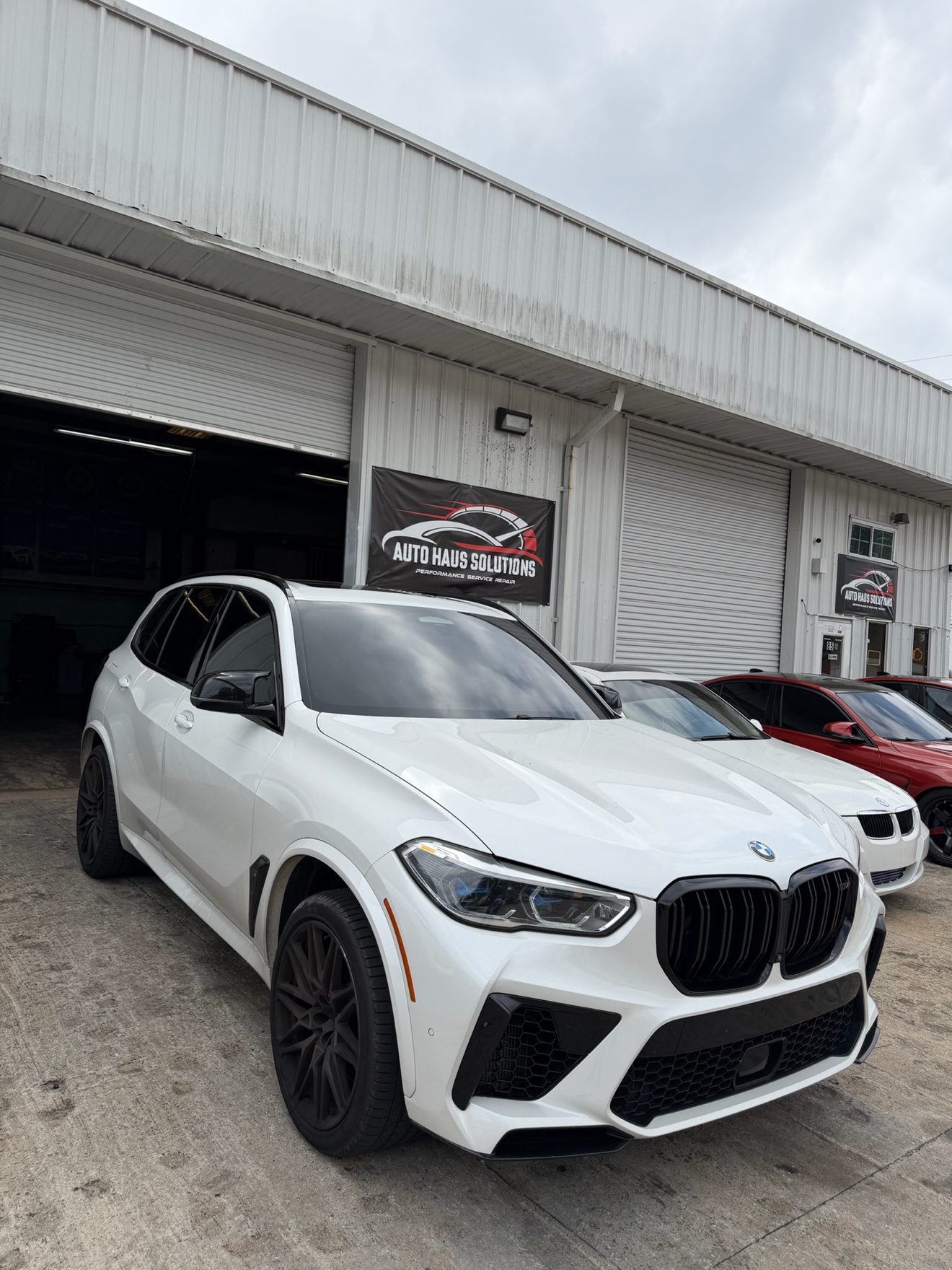 White BMW X5M SUV in front of Auto Haus Solutions